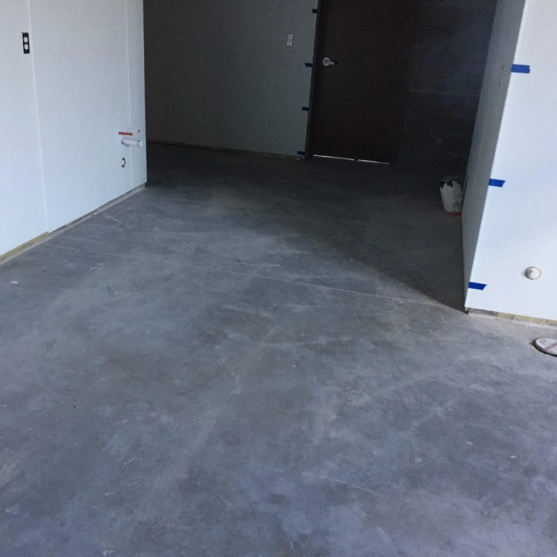 A close-up of a concrete floor prepared for slurry epoxy flooring. The smooth, gray concrete is clean and ready for the epoxy application