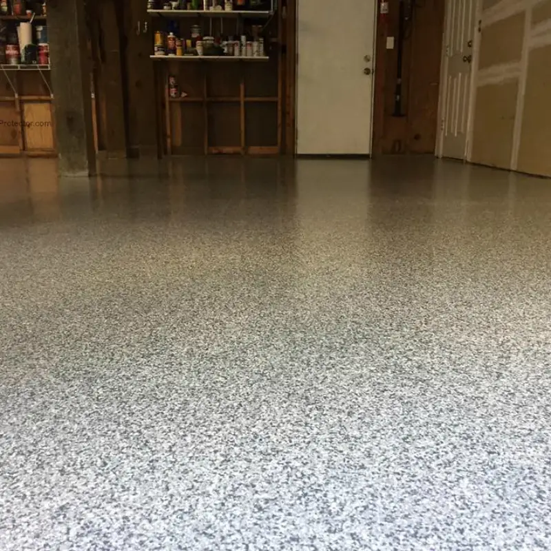 A graveled epoxy flooring system has been newly installed in a residential garage, featuring a shiny, speckled finish.
