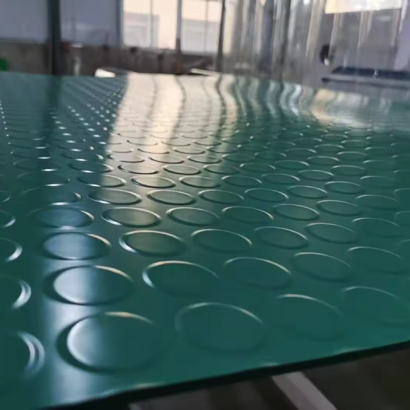 A piece of green rubberized epoxy flooring with a raised, circular tread pattern is shown up close.