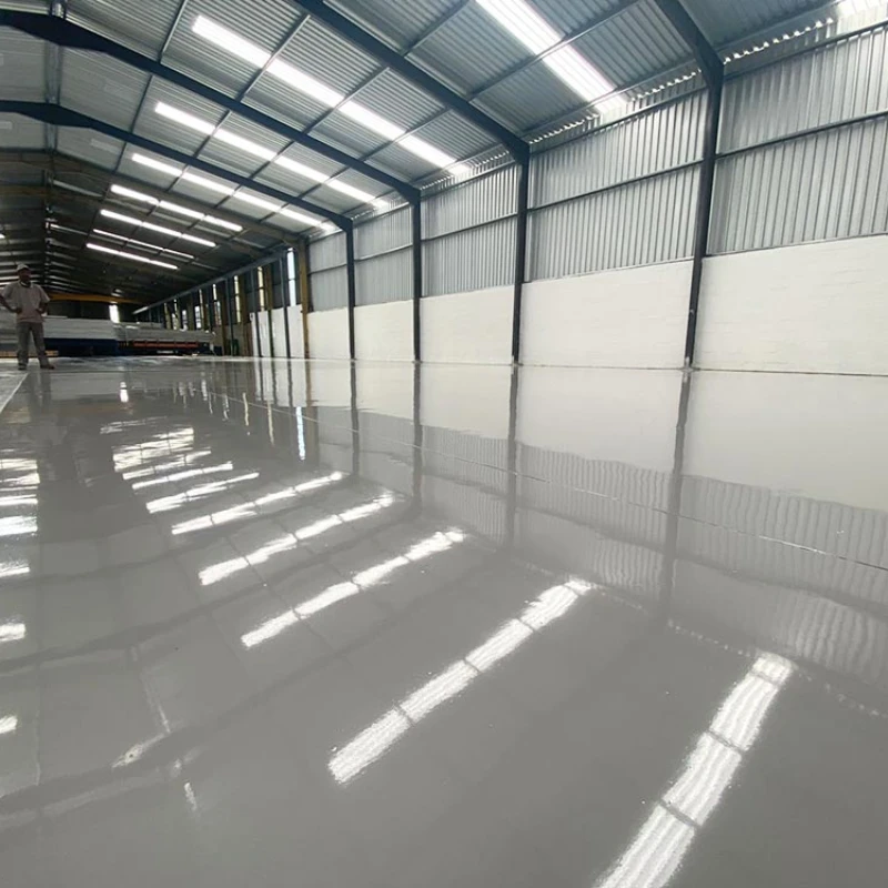 A wide-angle view of a newly installed, light-gray screed epoxy flooring inside a large industrial warehouse