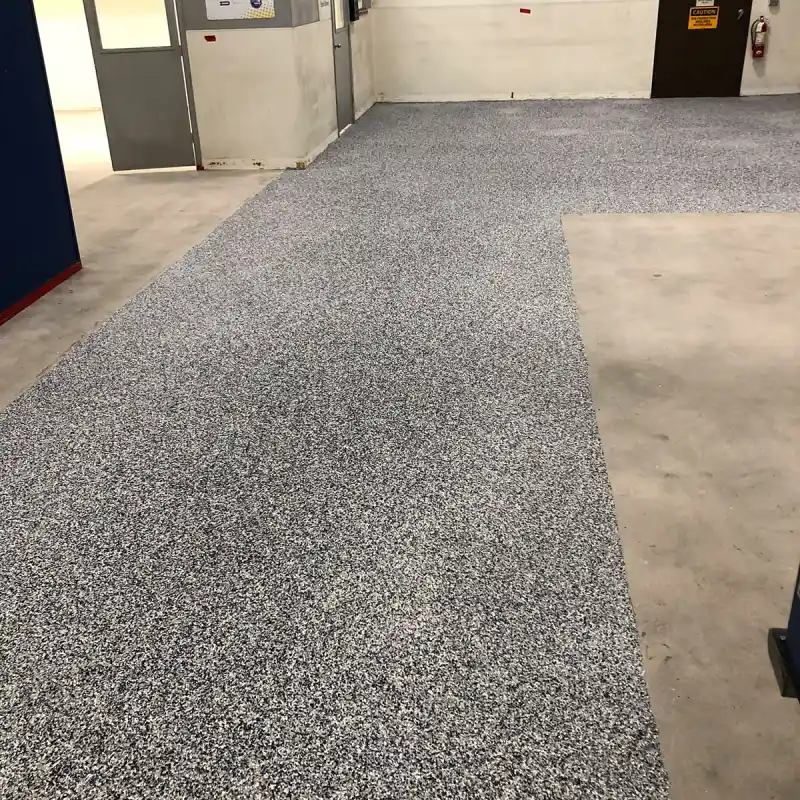 A low-angle, interior shot of a warehouse or industrial space with a newly installed slip-resistant epoxy flooring.