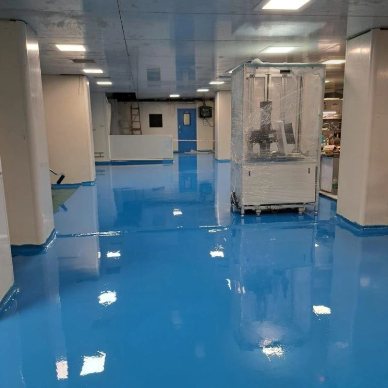 A wide-angle, interior shot of a cleanroom or industrial facility with a newly applied, highly reflective, food-grade epoxy flooring in a vibrant, bright blue.